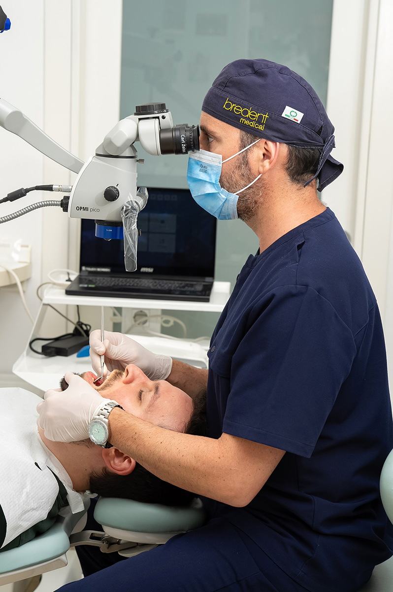 Dott. Pietro Leone al microscopio operatorio durante una visita parodontale